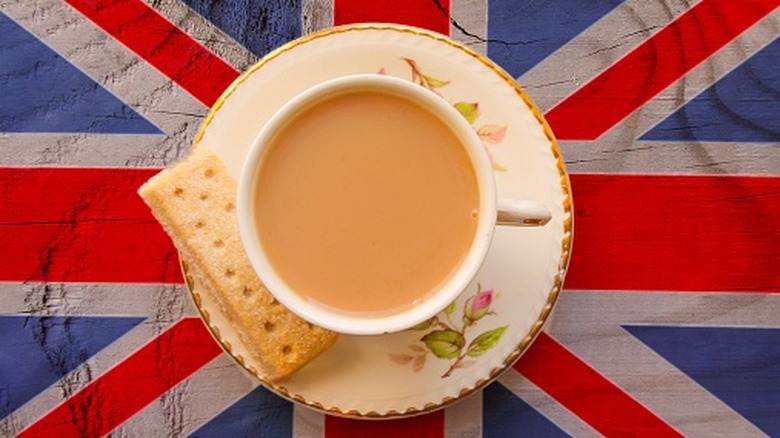 A cup of English Breakfast tea is seen from overhead with a shortbread next to it, on top of a Union Jack flag
