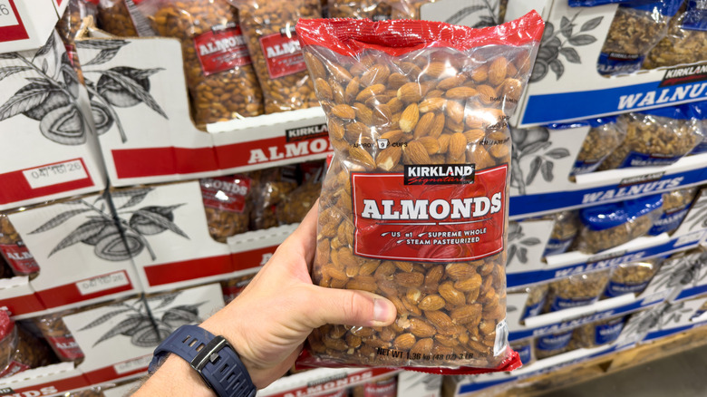 person holding bag of Kirkland almonds in front of store display