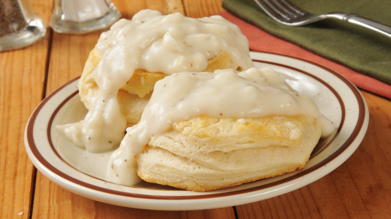 Close up of a plate containing flaky biscuits topped with creamy gravy
