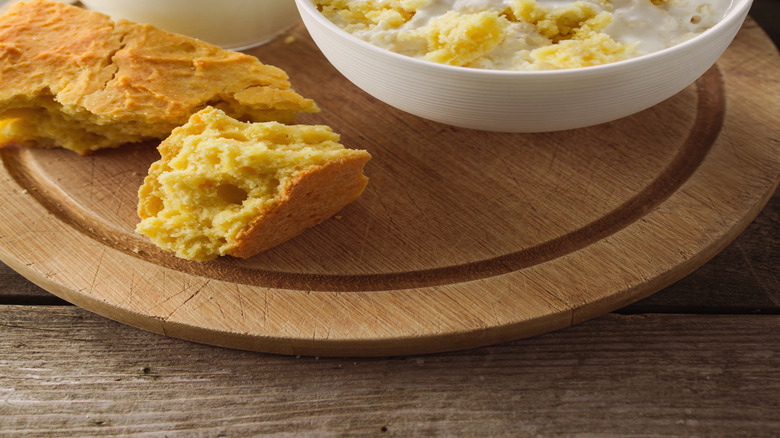 Close up of a bowl of cornbread and milk with cornbread and a jug of milk set to the side