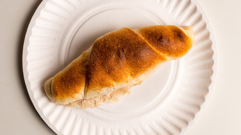 A homemade pepperoni roll on a white plate against a white background