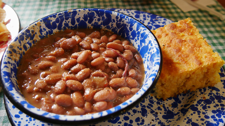 Bean soup in a blue patterned bowl, next to a piece of cornbread