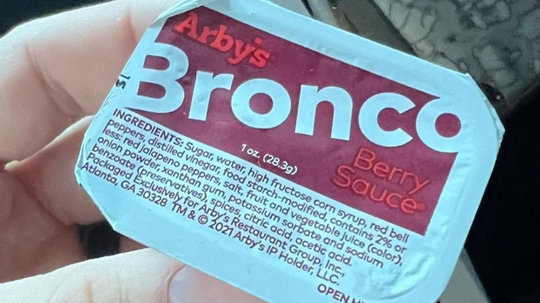 Close-up of someone holding a closed container of Arby's Bronco Berry sauce