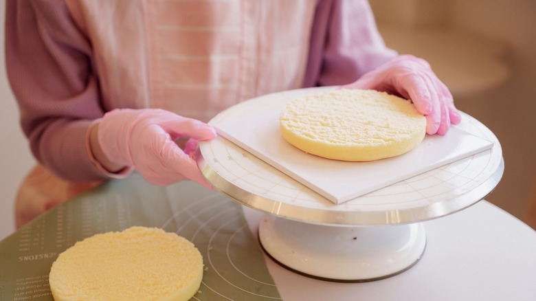 Baker placing vanilla cake on white cake turntable