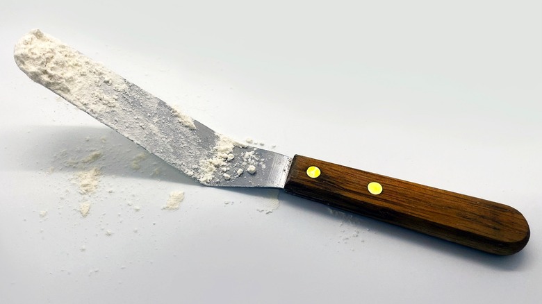 Baker spreading frosting onto a cake with an offset spatula