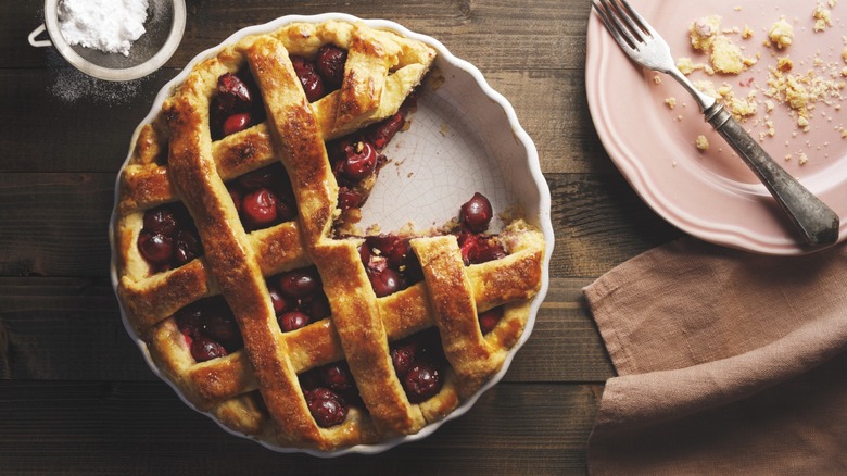 Person holding a strawberry pie in a vintage ceramic pie dish