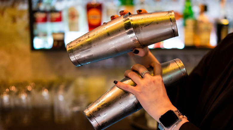 A bartender shakes two cocktails