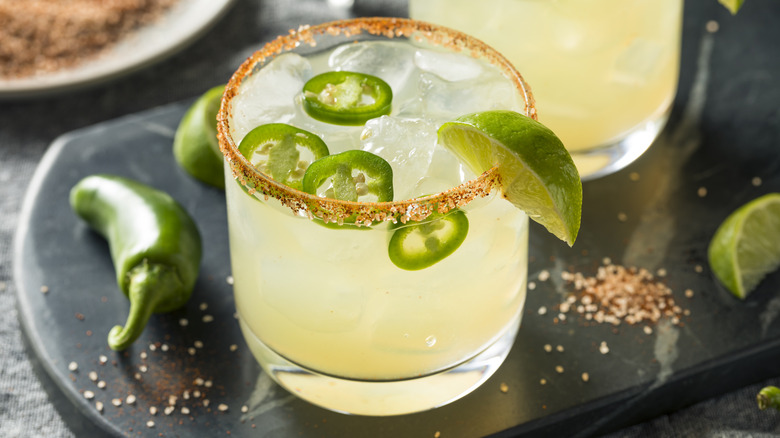 A margarita with jalapeño slices and a lime wedge
