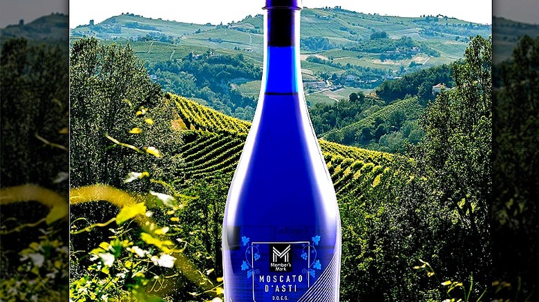 A blue bottle of Moscato d'asti with vineyards and hills in the background