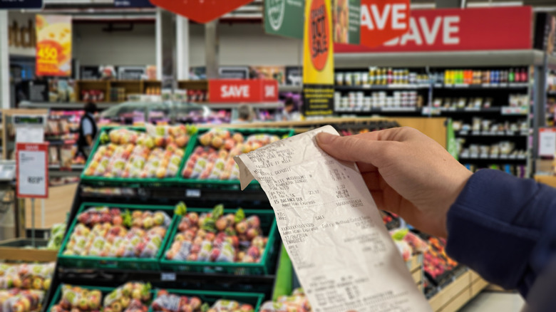 Man holding receipt in front of grocery store display