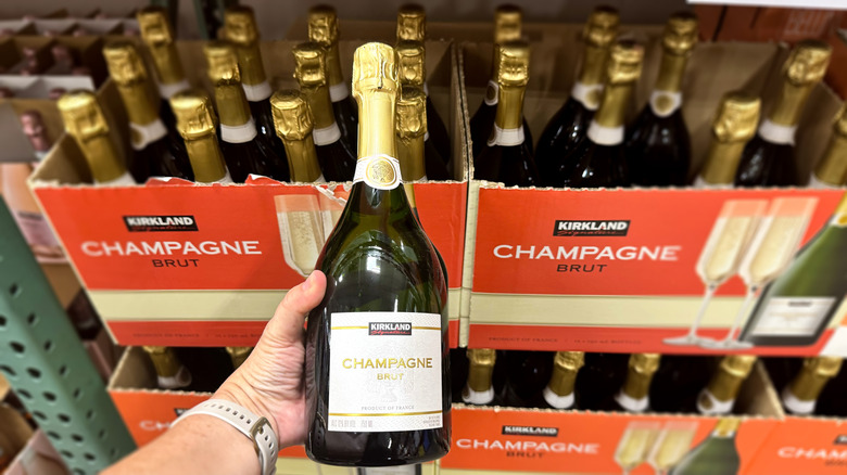 hand holding bottle of champagne in front of boxes