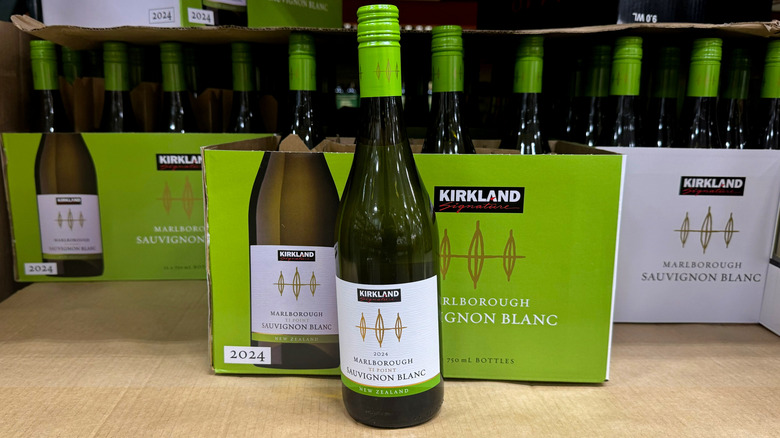 bottle of white wine on shelf in front of cases of wine