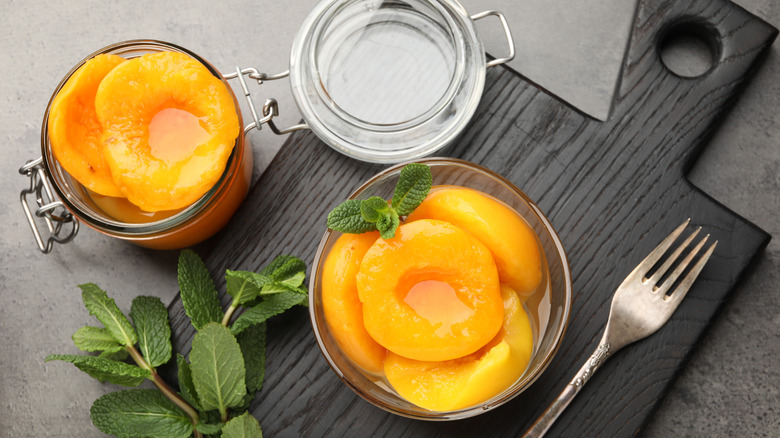 pickled peaches in a glass jar on cutting board