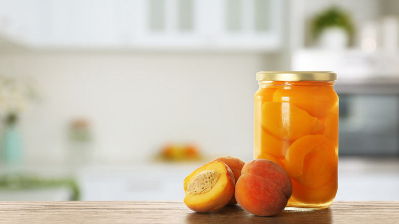 jar of pickled peaches with fresh peaches