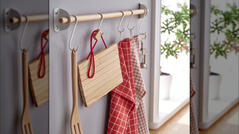 Expandable wooden trivet hanging from hook on kitchen rack