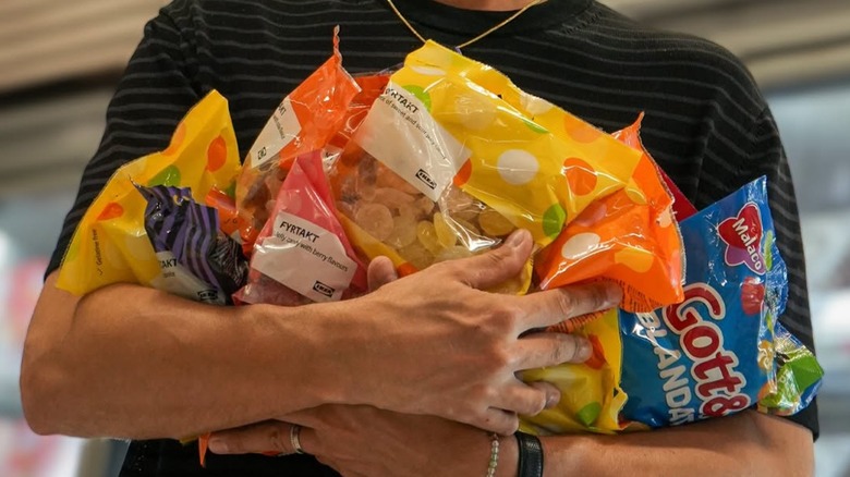 A person with their arms full of IKEA candy bags