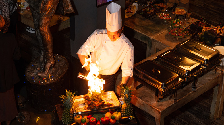 A chef flambées a dish at a buffet