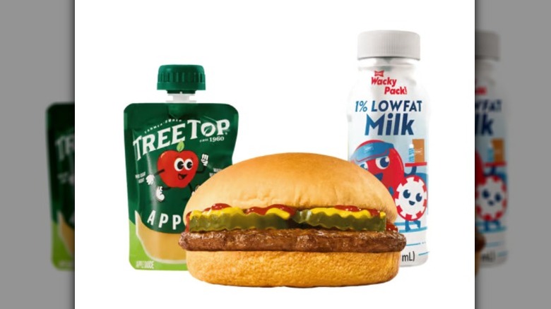 A Sonic hamburger, Treetop applesauce, and bottle of milk against a white background