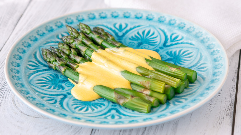 A plate of asparagus, topped with Hollandaise sauce