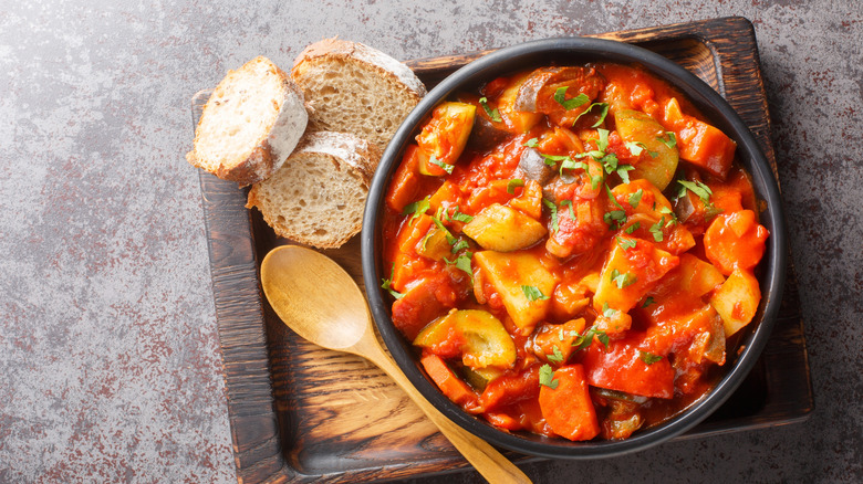 A vegetable stew with slices of bread on a wooden board