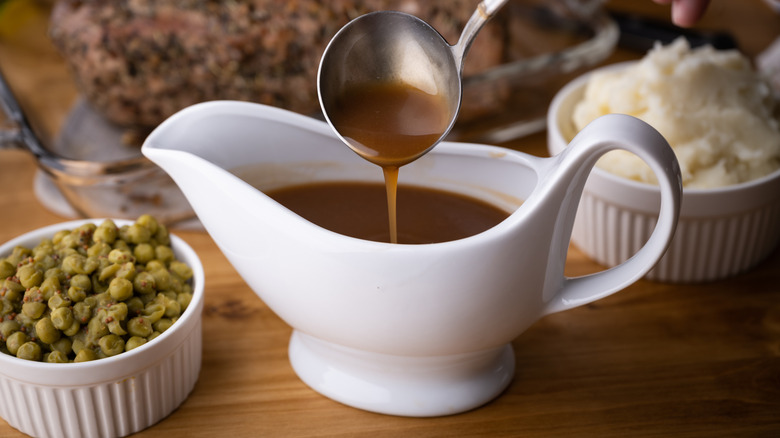 A ladle scoops gravy out of a jug
