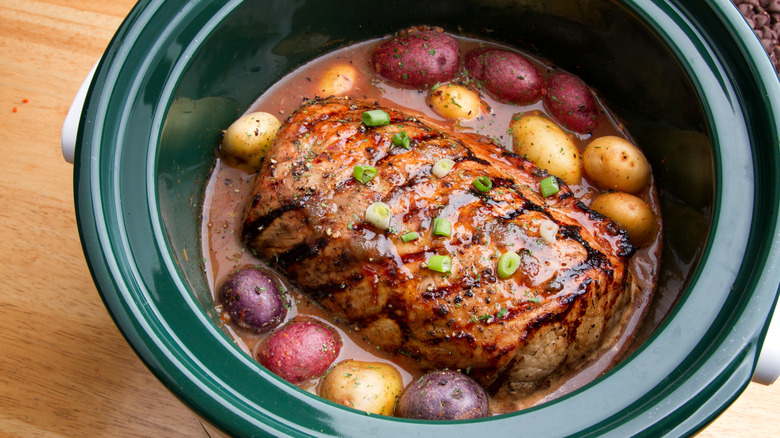 A pot roast with boiled potatoes in a slow cooker
