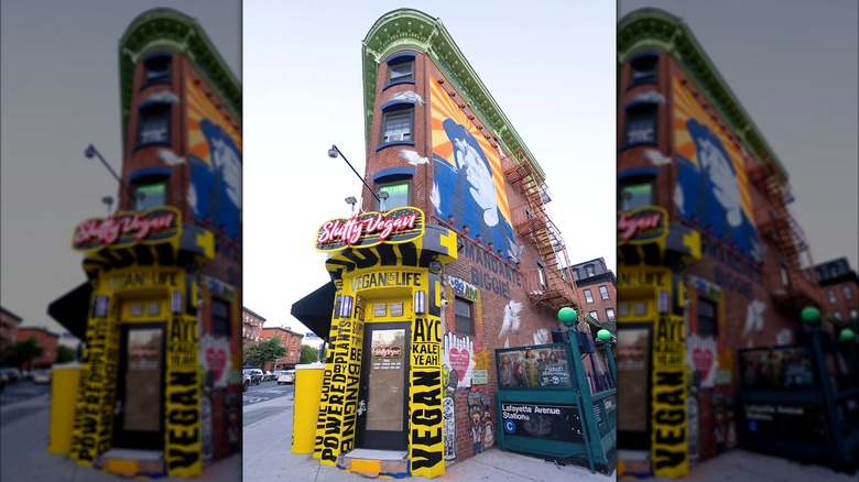 The exterior of Sl*tty Vegan in Brooklyn with colorful murals on the walls