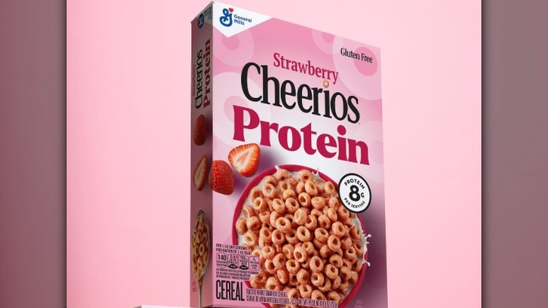 A box of strawberry Cheerios Protein against a pink background