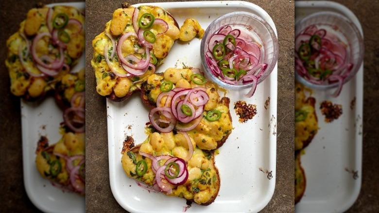 Overhead view of three pieces of toast with cheese, butter beans, and pickled red onions and jalapeño on a baking dish