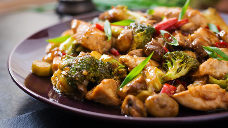 A plate full of stir fried chicken satay with veggies