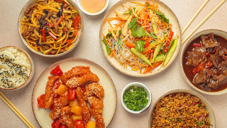 A variety of Chinese dishes set up on a table with chopsticks