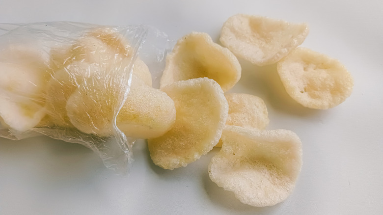 Prawn crackers spilling out of a clear plastic bag onto a white table