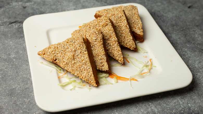 Sesame prawn toast on a white plate placed on a table