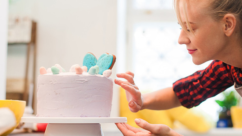 A woman decorating a pink cake placed on a turntable