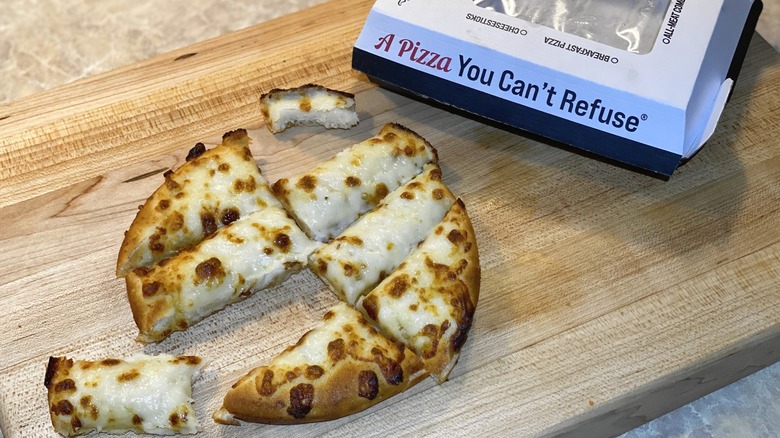 A Godfather's Pizza box next to a round piece of cheese bread cut into slices