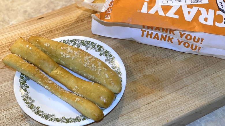 Little Caesars Crazy Bread bag next to a plate of breadsticks