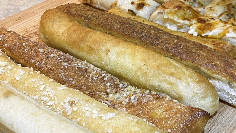 Breadsticks lined up on cutting board