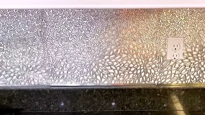 Intricate silver placemats used as backsplash in kitchen