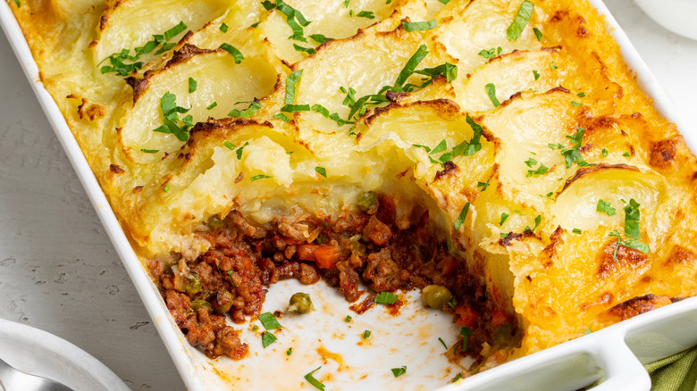 Close up of a casserole dish of cottage pie with a piece cut out of it