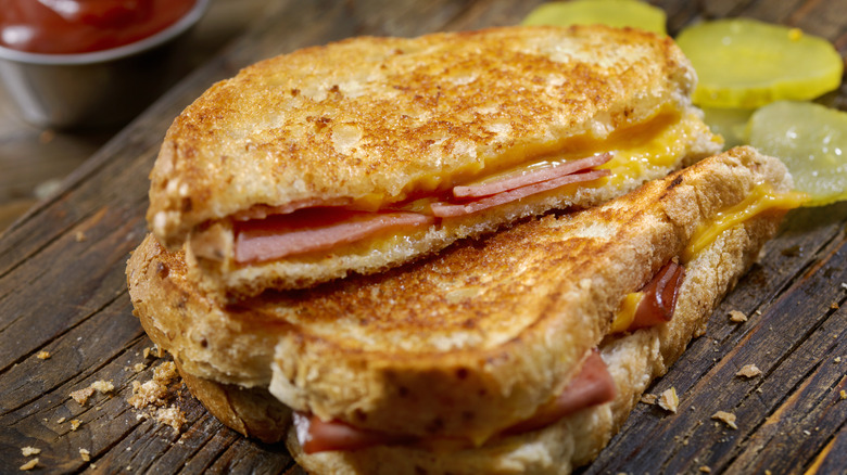 A fried bologna and cheese sandwich cut in half on a wooden surface