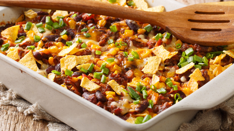Close up image of a Frito Pie with a wooden spoon laying over top