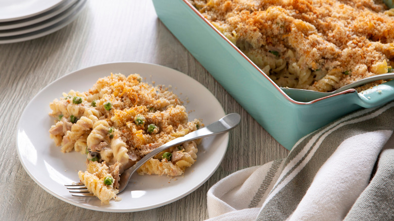 A plate of tuna noodle casserole next to a casserole dish
