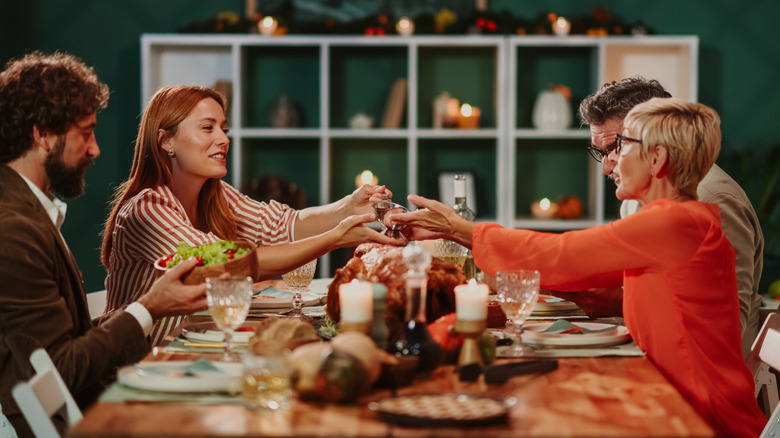 A family sits at a dinner table, with one person passing the salt to another