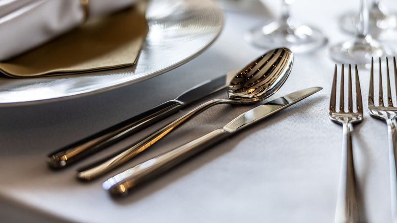 Silver cutlery sits next to a plate