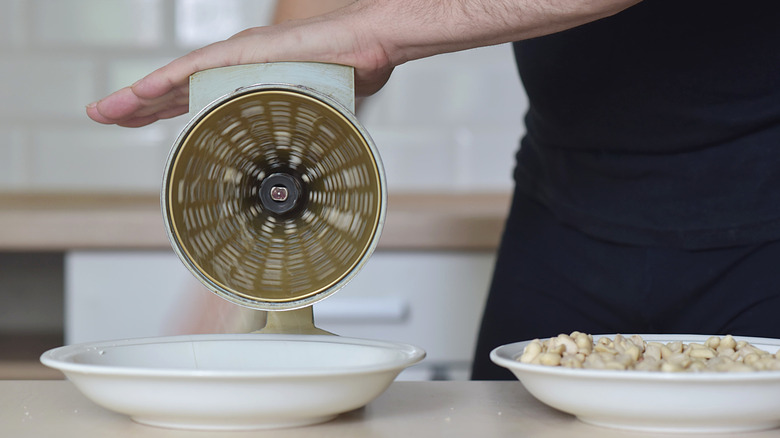 A person operating a vintage nut grinder