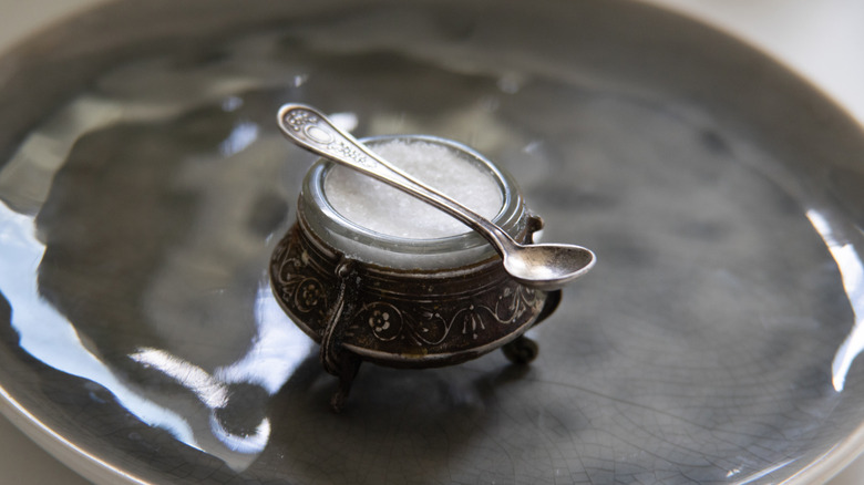 A vintage salt cellar with a serving spoon