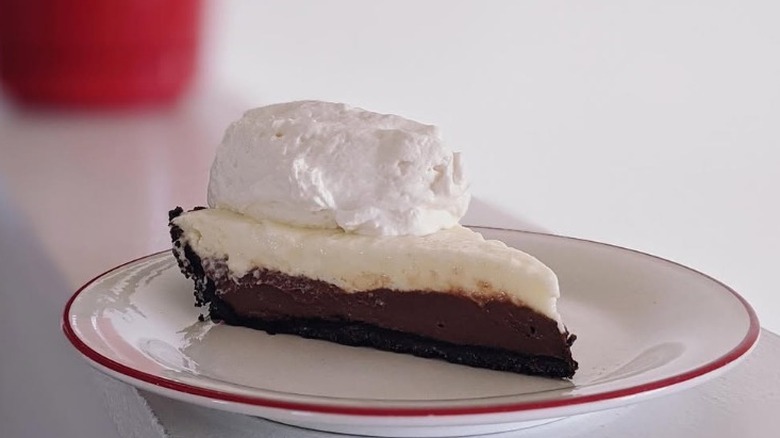 Black bottom pie on a white plate topped with whipped cream