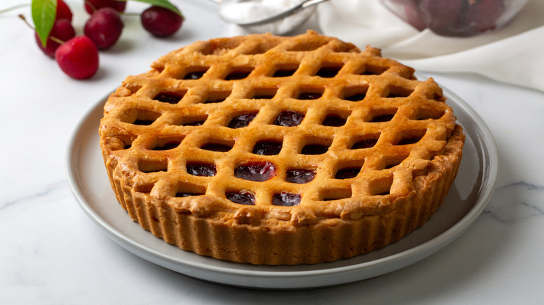 Cherry pie on a white plate placed on a marble table