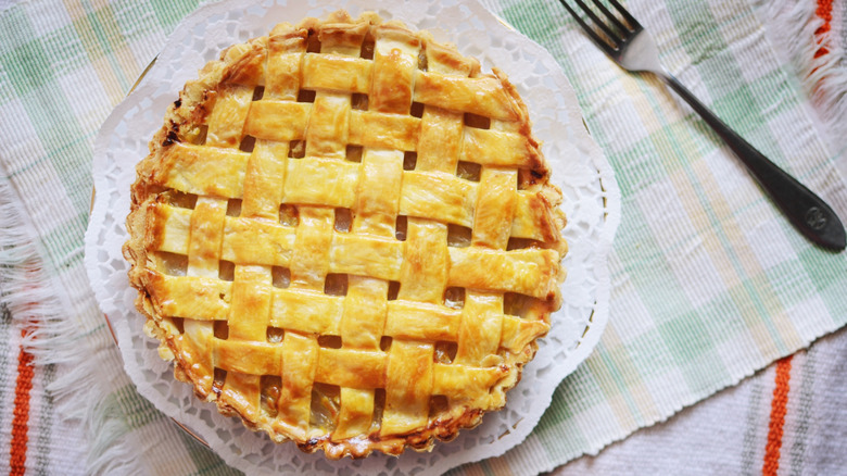Pineapple pie with lattice work placed on a table with a fork on the side