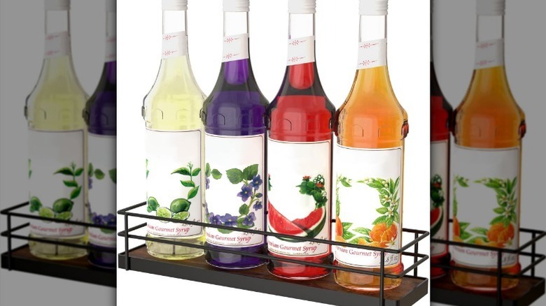 Syrup organizer rack with four bottles of lime, watermelon, orange and purple flavors on white background